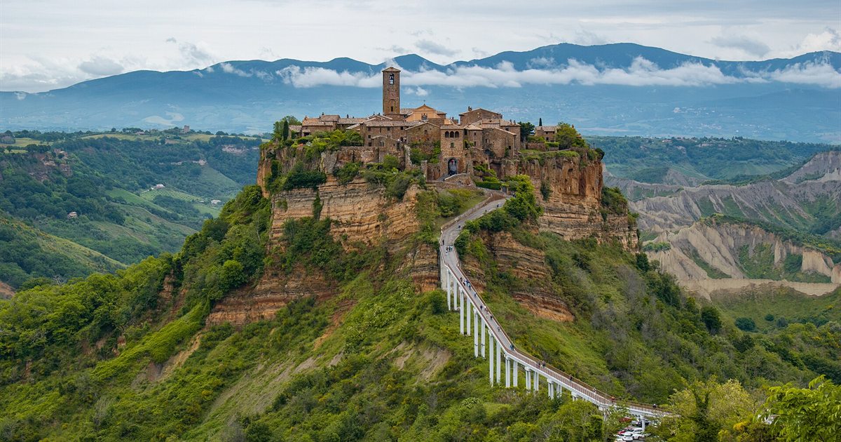 Civita di Bagnoregio sulla rupe di tufo con il lungo ponte pedonale nella Valle dei Calanchi