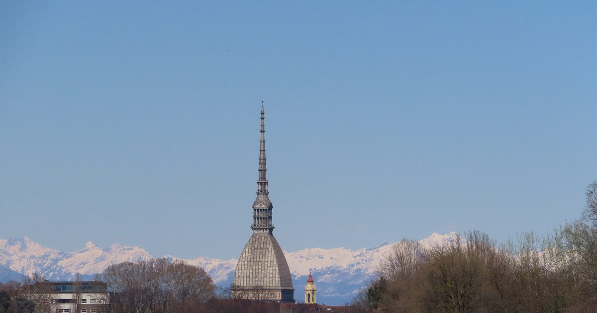 La Mole Antonelliana sopra i tetti di Torino con le Alpi innevate sullo sfondo
